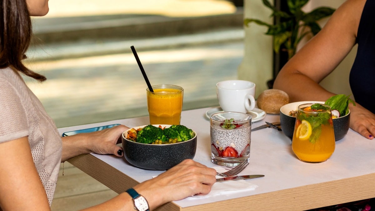 Two woman eating tasty chicken salads with dessert